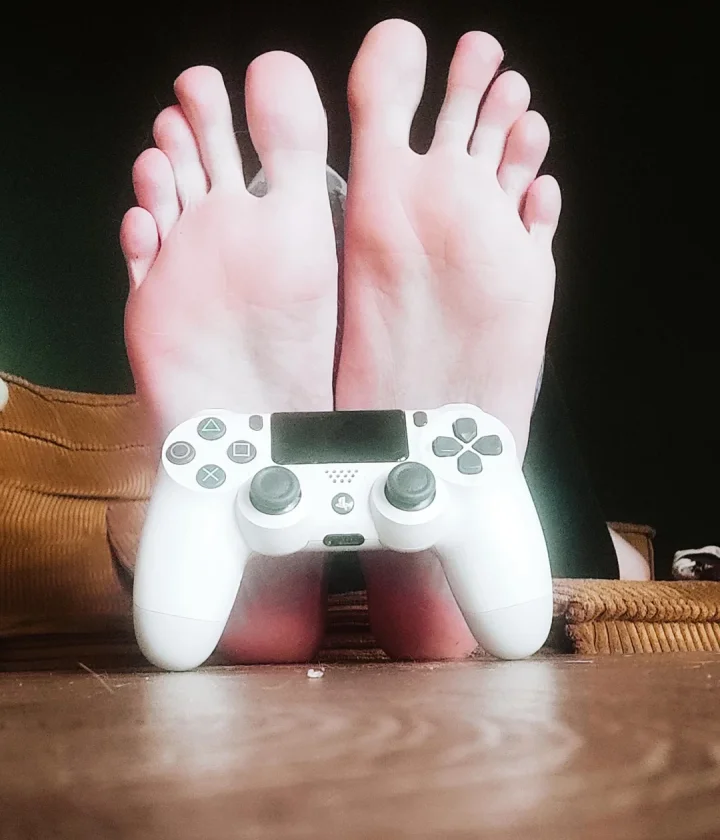 Size 11 vs PlayStation controller – who wins? 😏 – Sitting picture of GoddessBlondie (@goddessblondiefeet)